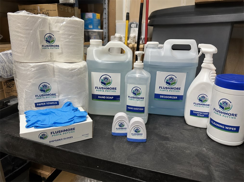 Paper towels, gallon hand soap and sanitizer refills, disinfectant spray and cleaning wipes on a stockroom bench